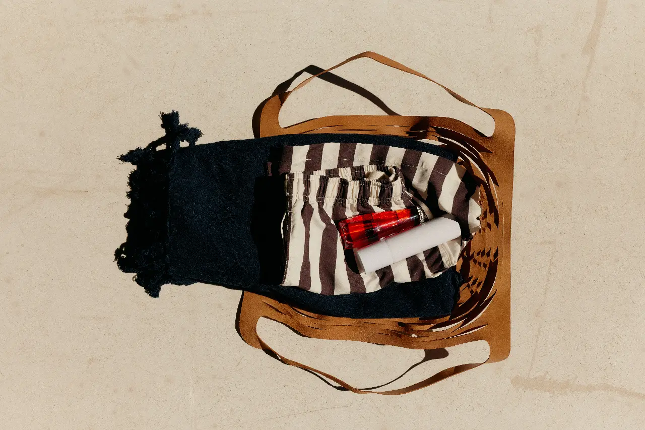 Open woven tote holding neatly packed fabric and small travel items