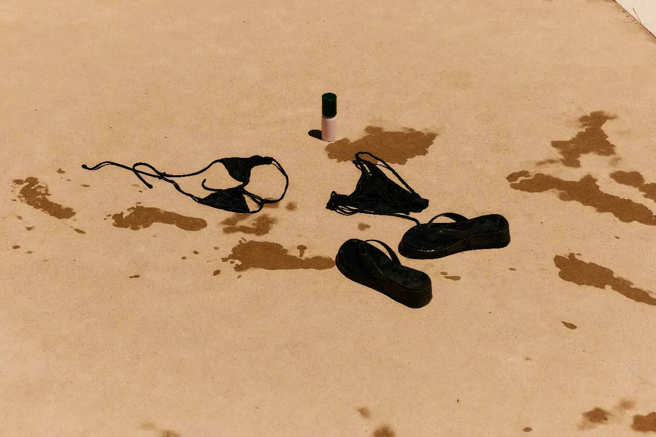 Personal items arranged on sunlit pavement beside water marks